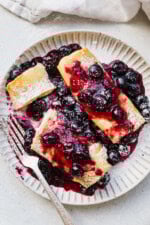Cooked cheese blintzes on plate with blueberry sauce