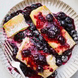 Cooked cheese blintzes on plate with blueberry sauce
