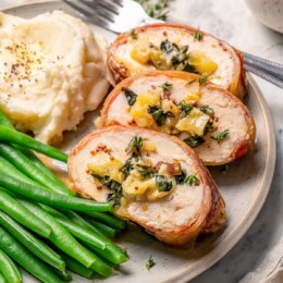 Three slices of prosciutto-wrapped stuffed turkey tenderloin with kale and apple.