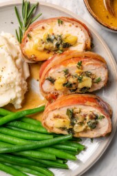 Plate with prosciutto-wrapped stuffed turkey tenderloin, green beans, and mashed potatoes.