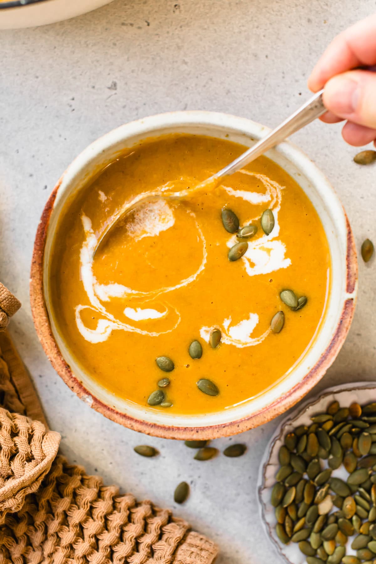 Pumpkin Ginger Coconut Soup topped with a swirl of coconut milk and pepitas.