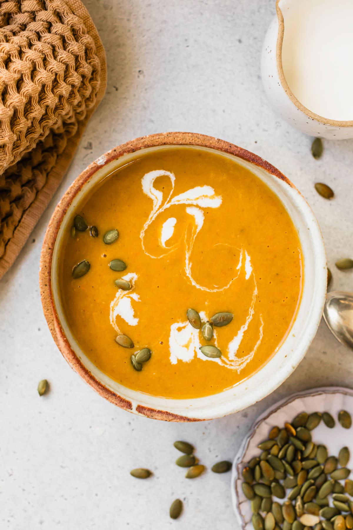 Pumpkin Ginger Coconut Soup topped with a swirl of coconut milk and pepitas.