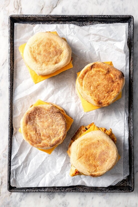 This Chick-Fil-A Egg White Grill copycat is made with juicy grilled chicken, fluffy egg whites and cheese for a hearty meal prep breakfast! 4 copycat Chick-fil-A egg white grill sandwiches on parchment lined sheet pan.