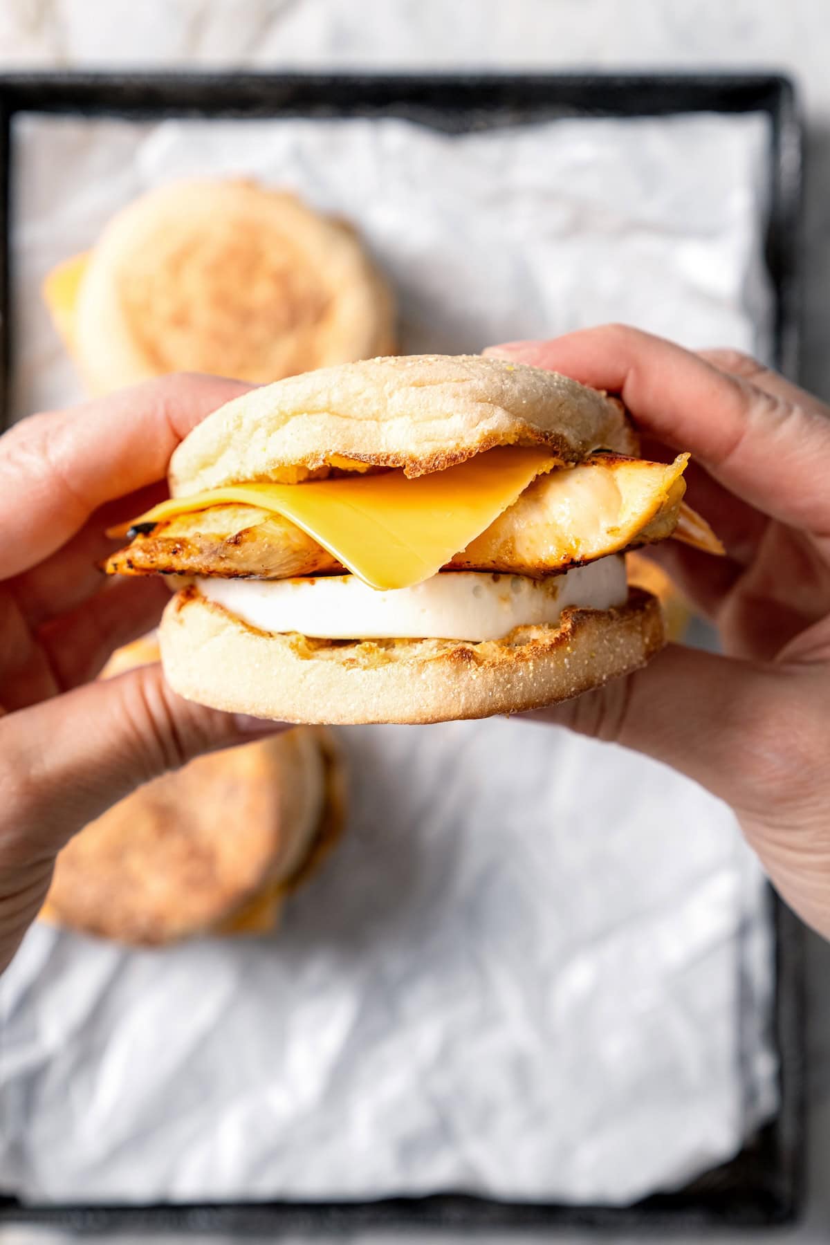 This Chick-Fil-A Egg White Grill copycat is made with juicy grilled chicken, fluffy egg whites and cheese for a hearty meal prep breakfast! Two hands holding egg white grill breakfast sandwich.